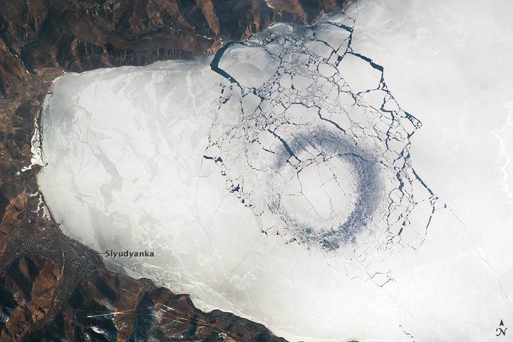 Astronaut photograph of a large dark circular pattern in the ice of Lake Baikal